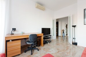 A modern room with a wooden desk, a chair, a television, and a lamp.