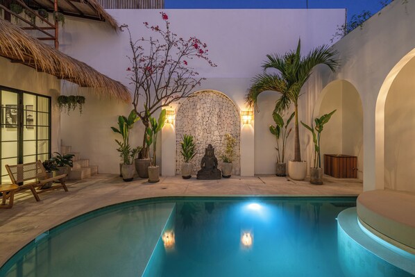 A swimming pool with a stone wall and potted plants.