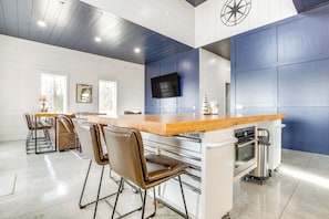 Modern kitchen and dining area with oven, stainless steel sink, and mounted TV.