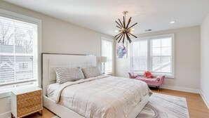 Un dormitorio con una cama grande, un aparador, una silla y una lámpara en el techo.