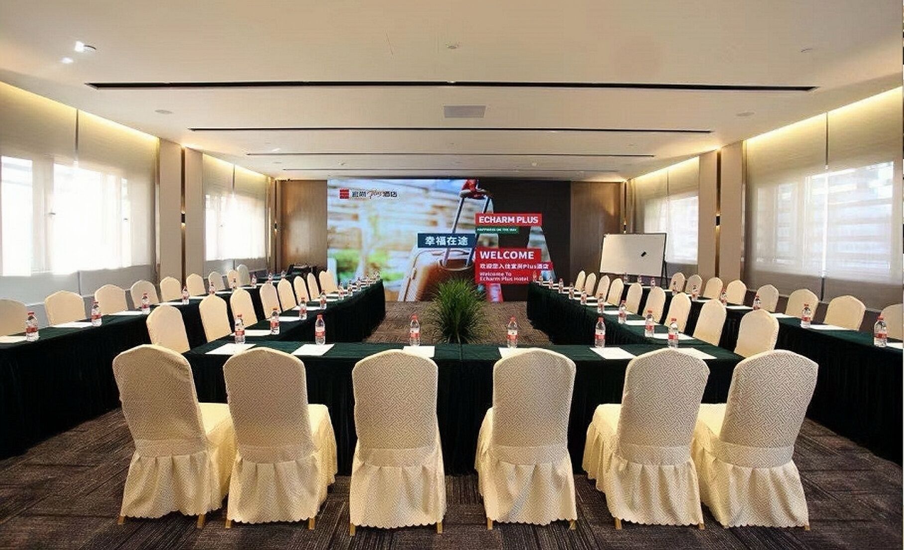A conference room with a long table, chairs, and a projection screen.