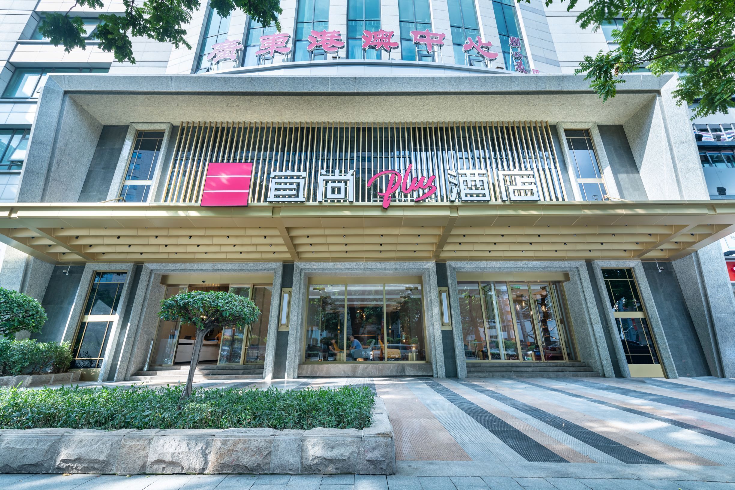 A modern building with a large entrance and a sign that reads "Xingda Plus Hotel".