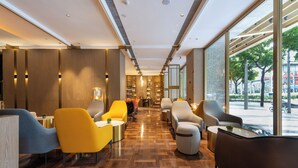 Un intérieur moderne avec un plancher en bois, des chaises jaunes et grises, et une grande fenêtre donnant sur la rue.