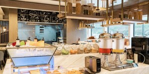 Una cafetería moderna con varios dispensadores de café, una máquina de café y una vitrina con pasteles.