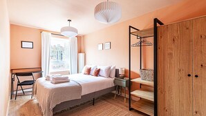 Ein Schlafzimmer mit Bett, Nachttisch, Kleiderschrank und einem Fenster mit Vorhängen.