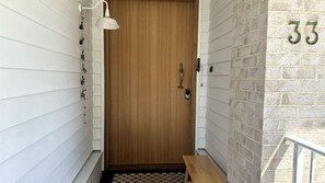 A wooden door with a brass handle, a small bench, and a mailbox on the right side.