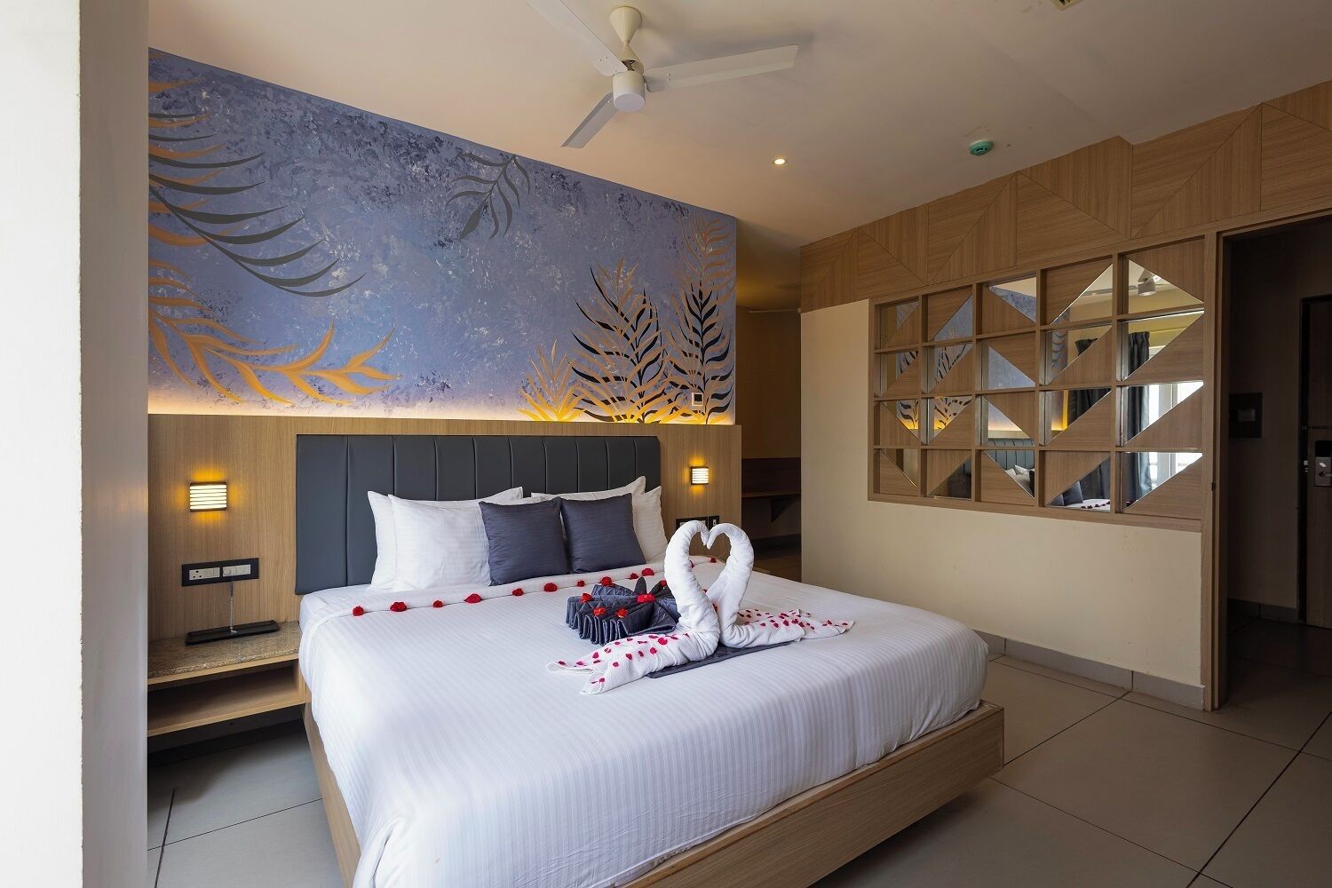 Een moderne hotelkamer met een groot bed, een plafondventilator en een decoratief muurschilderij.