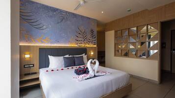 Een moderne hotelkamer met een groot bed, een plafondventilator en een decoratief muurschilderij.