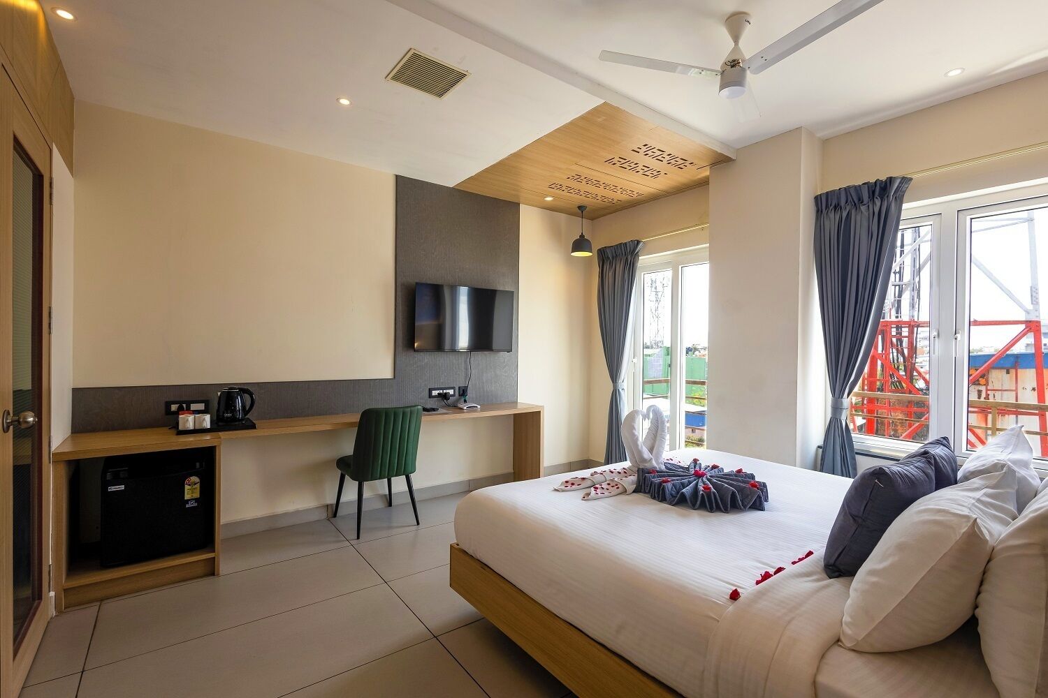 Une chambre d’hôtel avec un lit, un bureau, une chaise, une télévision et une fenêtre avec des rideaux.