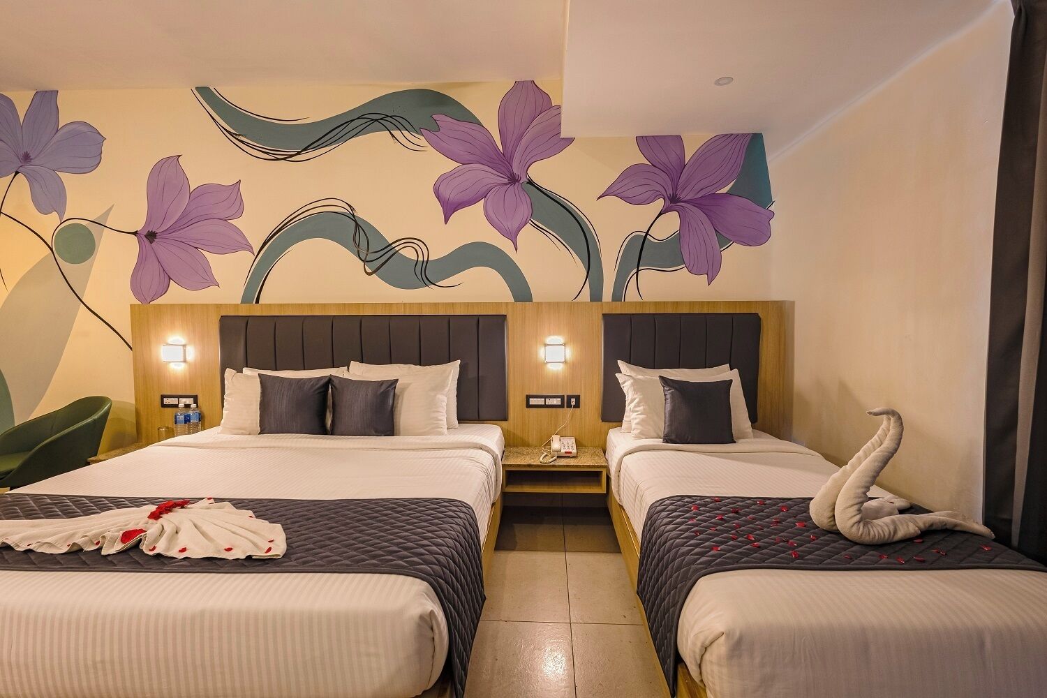 Habitación de hotel con dos camas, un mural en la pared y una decoración de toallas con forma de cisne.