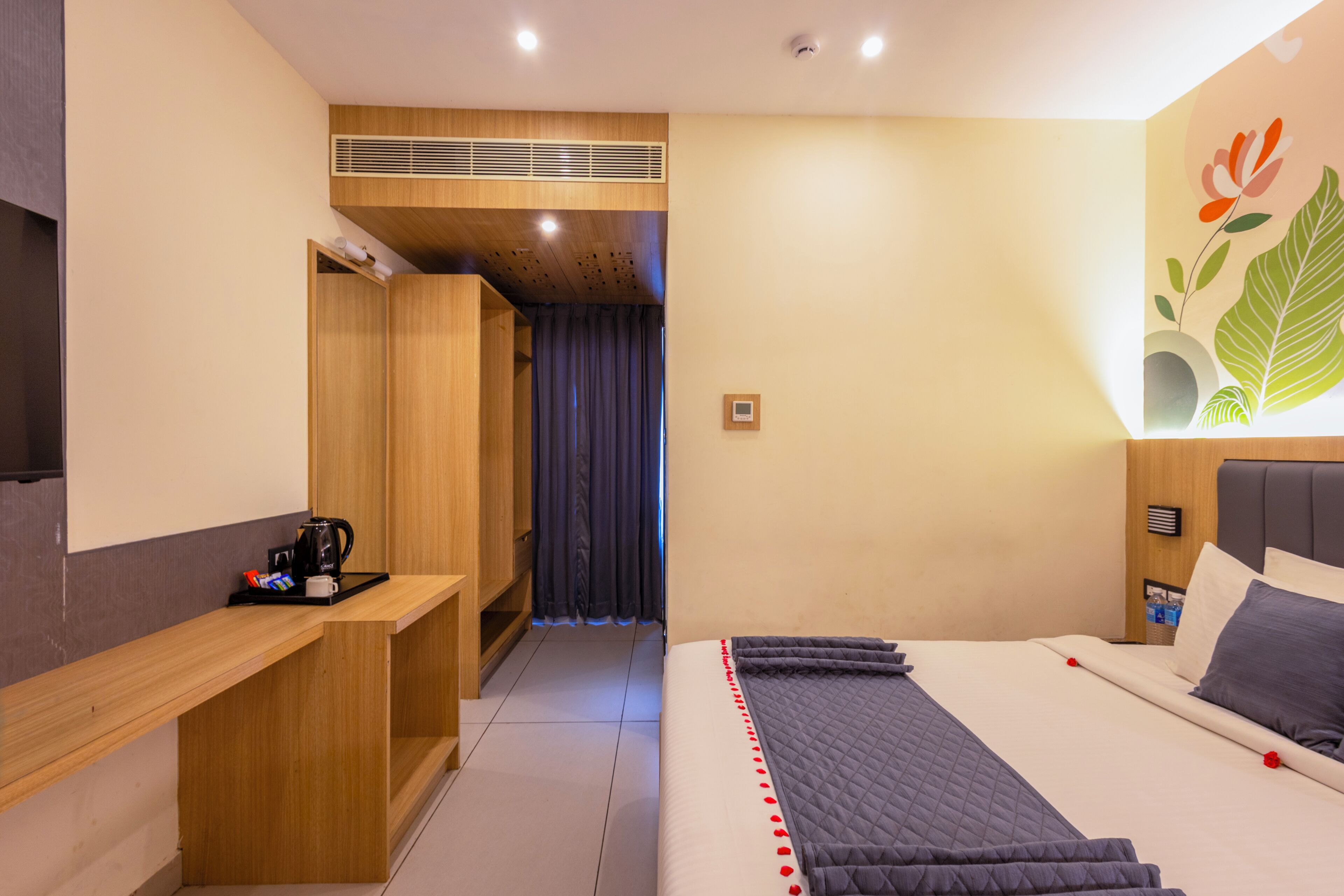 A modern hotel room with a bed, a desk, a shower area, and a bathroom.