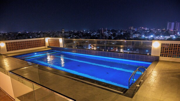 A rooftop pool with a city view at night. - HOTEL TAMIZH GRAND (Puducherry)