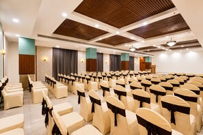 Un salón de conferencias con filas de sillas, un atril y un escenario.