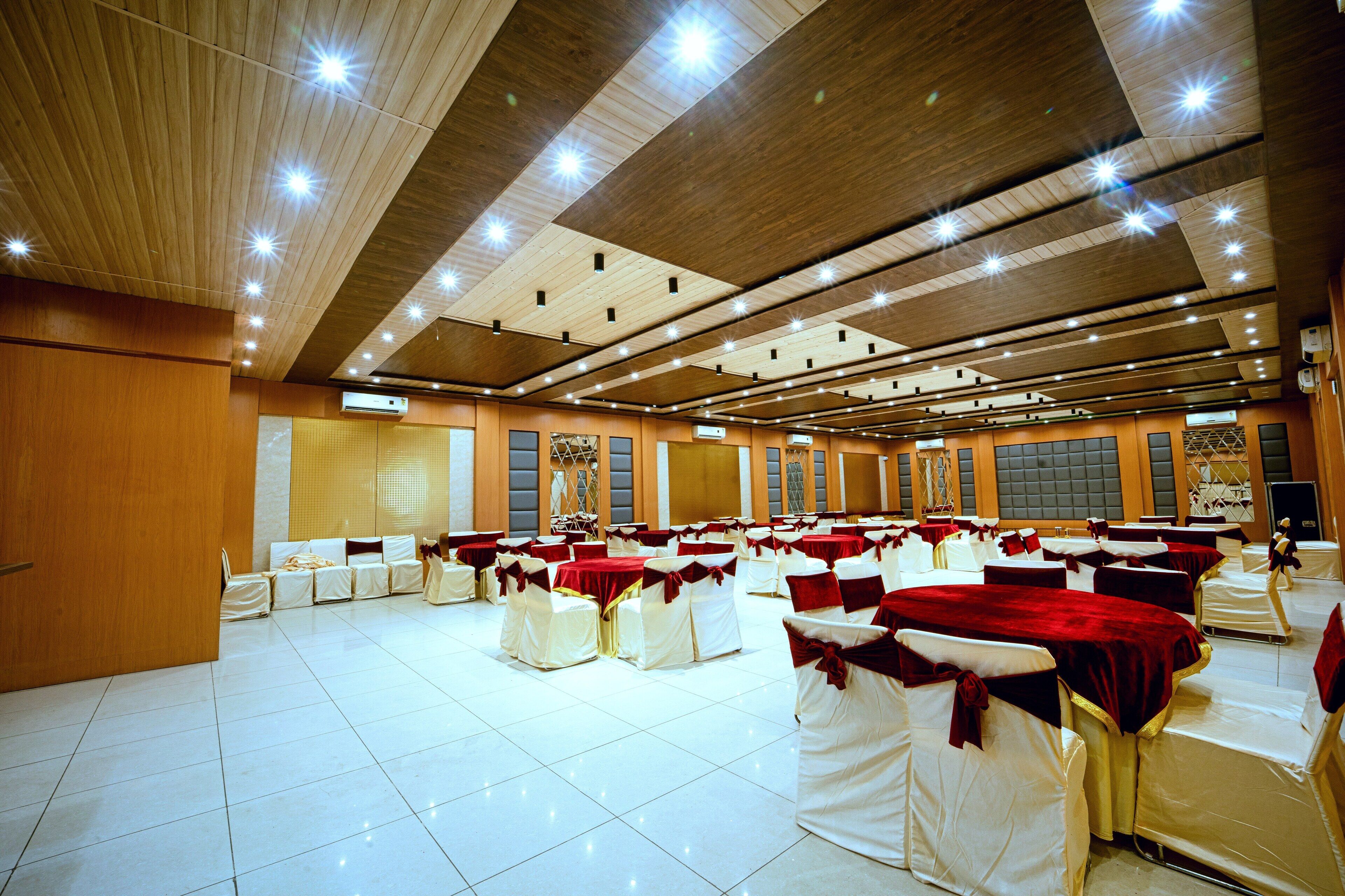 Un salón de banquetes con filas de mesas y sillas, techo de madera e iluminación empotrada.