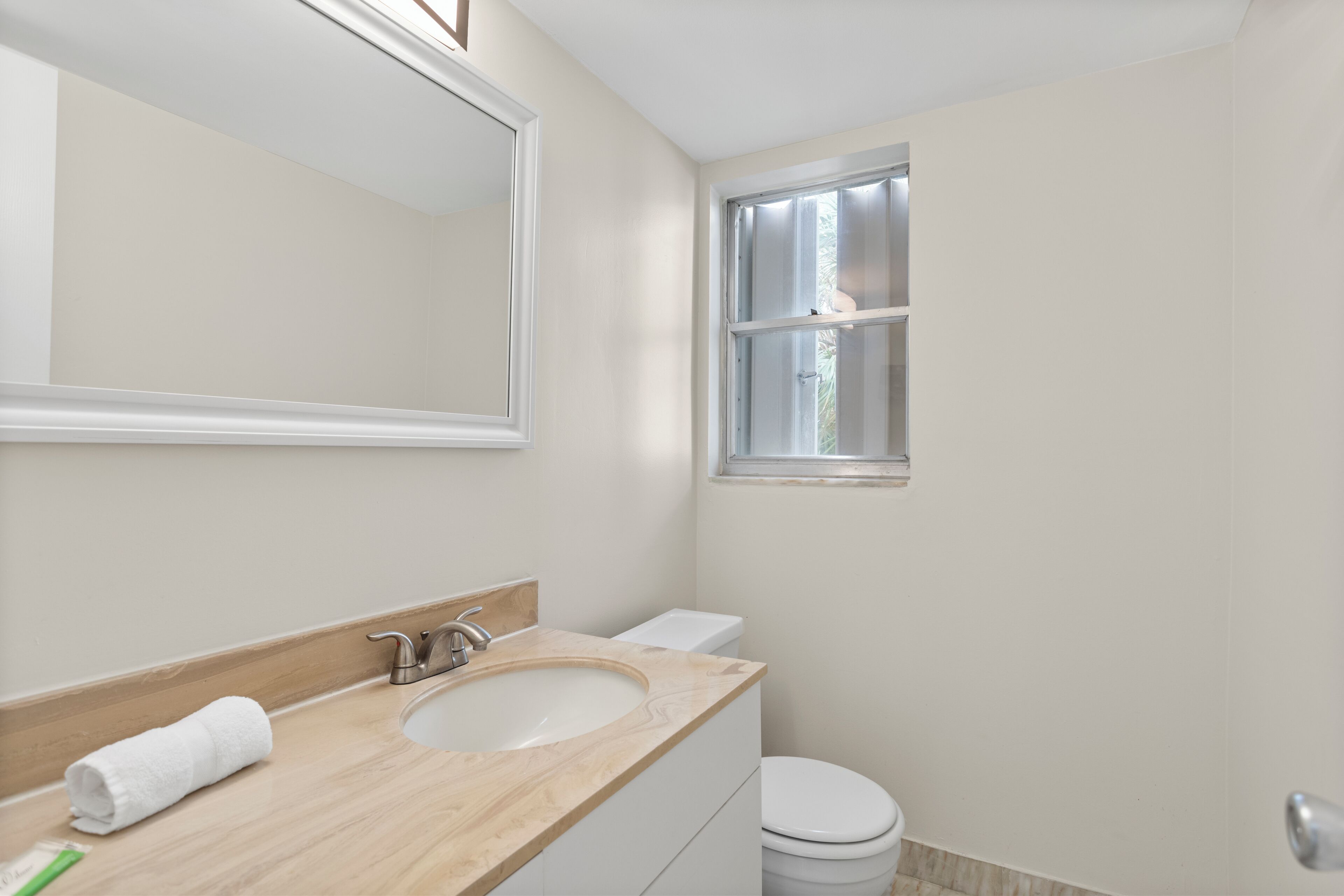 Une salle de bain avec un meuble-lavabo en bois, un évier, des toilettes et une fenêtre.