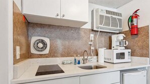 Een kitchenette met een magnetron, koffiezetapparaat en ventilator.