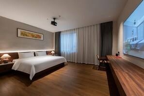 A modern hotel room with a large bed, wooden flooring, a desk, and a large window with curtains. - Foshan Anximan Yuansu Hotel - Lanshi (Foshan)