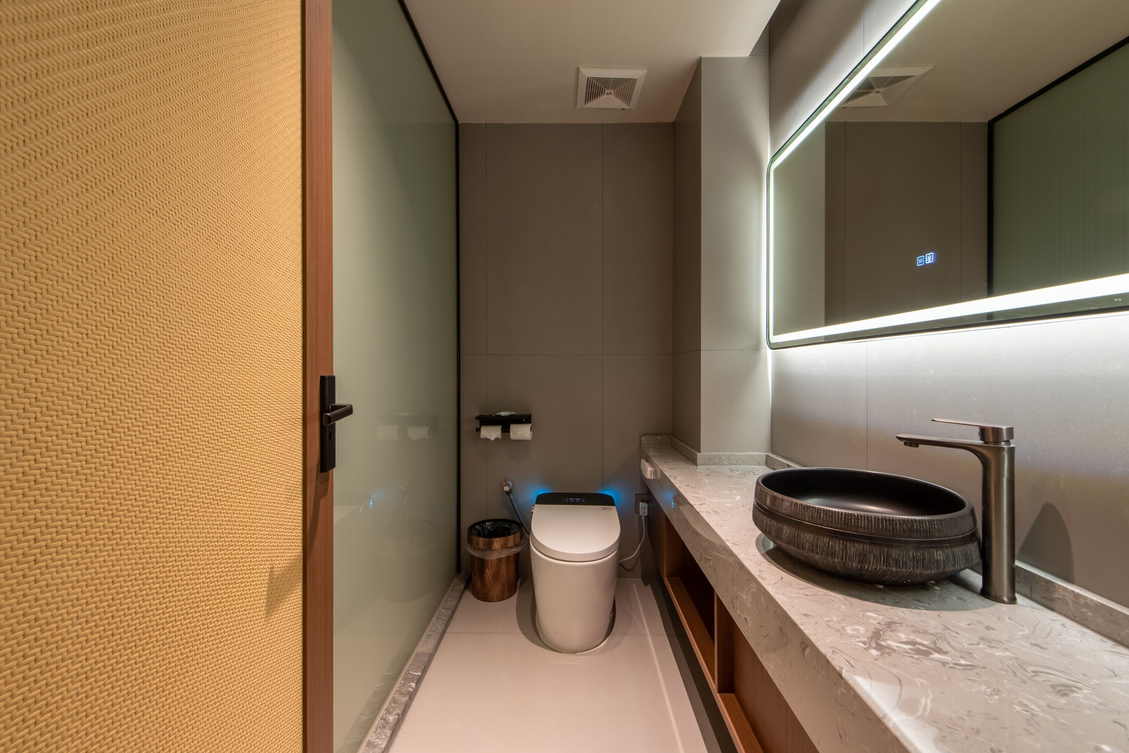 Une salle de bain moderne équipée de toilettes, d’un bidet et d’un grand miroir.