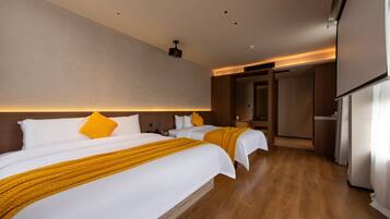 Habitación de hotel con dos camas, piso de madera, una lámpara de techo moderna y una puerta que da a otra habitación.