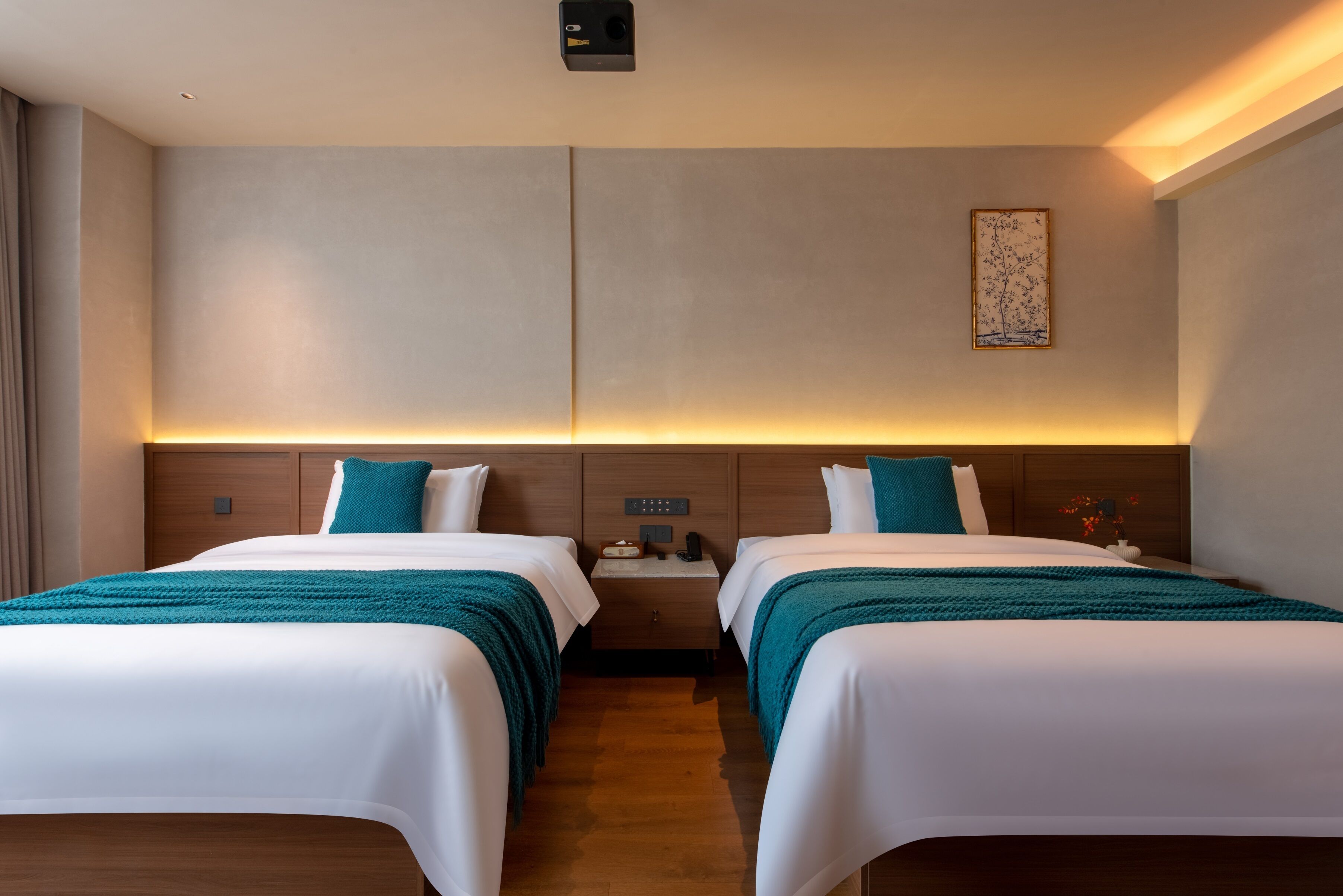 A hotel room with two beds, a nightstand, and a wall-mounted light fixture.