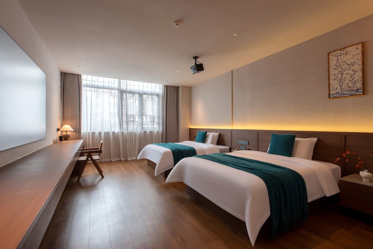 Ein Hotelzimmer mit zwei Betten, einem Schreibtisch und einem großen Fenster.