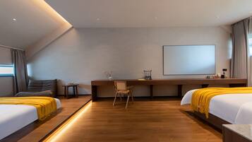 A modern hotel room with two beds, a desk, a chair, and a large screen.