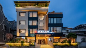 Un hotel moderno con techo plano, amplias ventanas y una entrada bien iluminada.