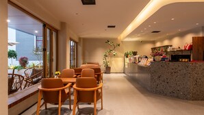 Un moderno vestíbulo de hotel con mostrador de recepción, zona de estar y grandes ventanales con vistas a la ciudad.