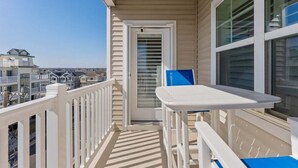 A balcony with a white railing, a table, and a chair. - Residence 304S at The Sandcastle Condominiums (Wildwood Crest)