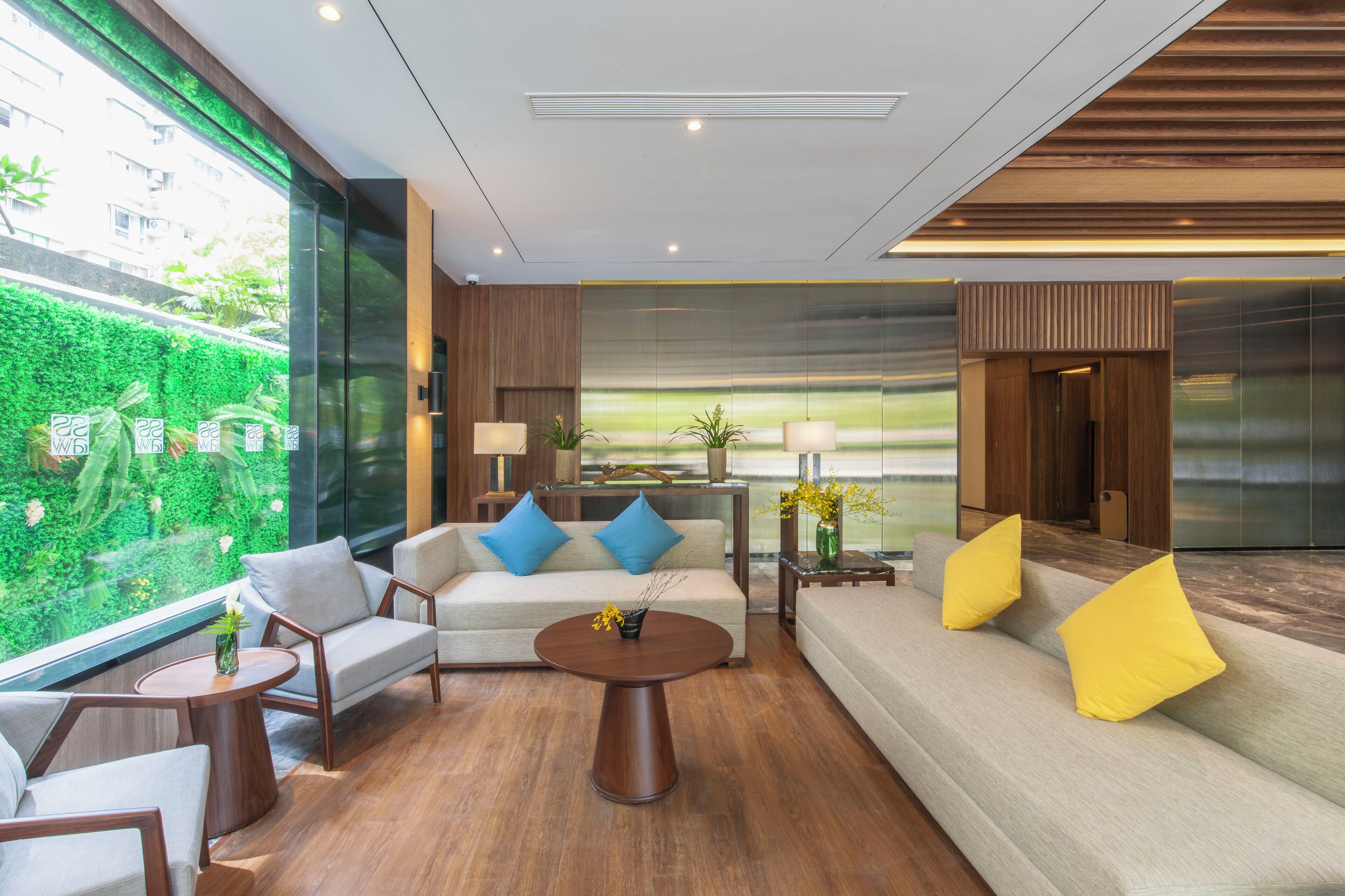 A modern lobby with a sofa, chairs, a coffee table, and a large window with a view of greenery.