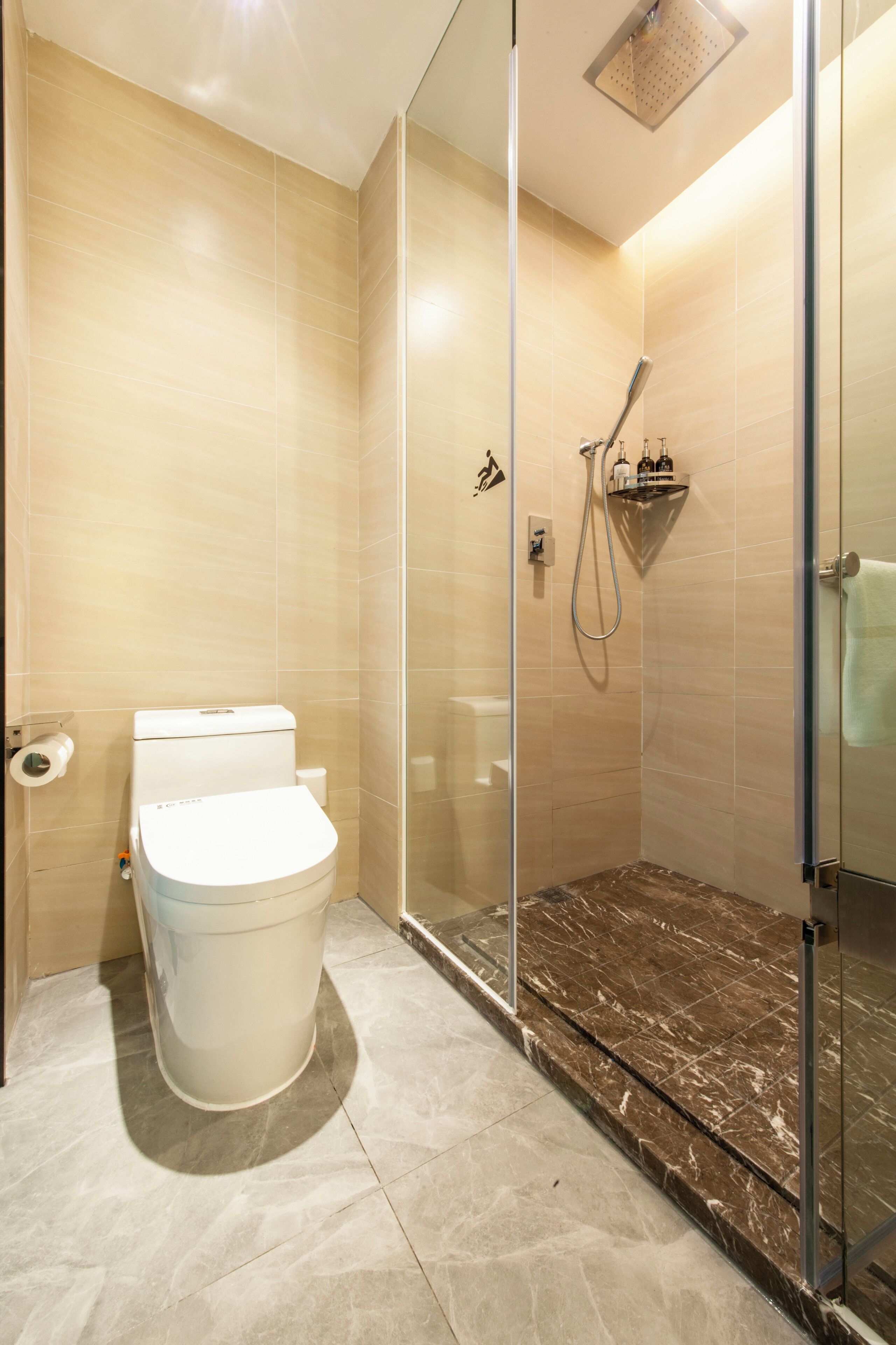 Un baño moderno con ducha envuelta en vidrio, inodoro y suelo de mármol.