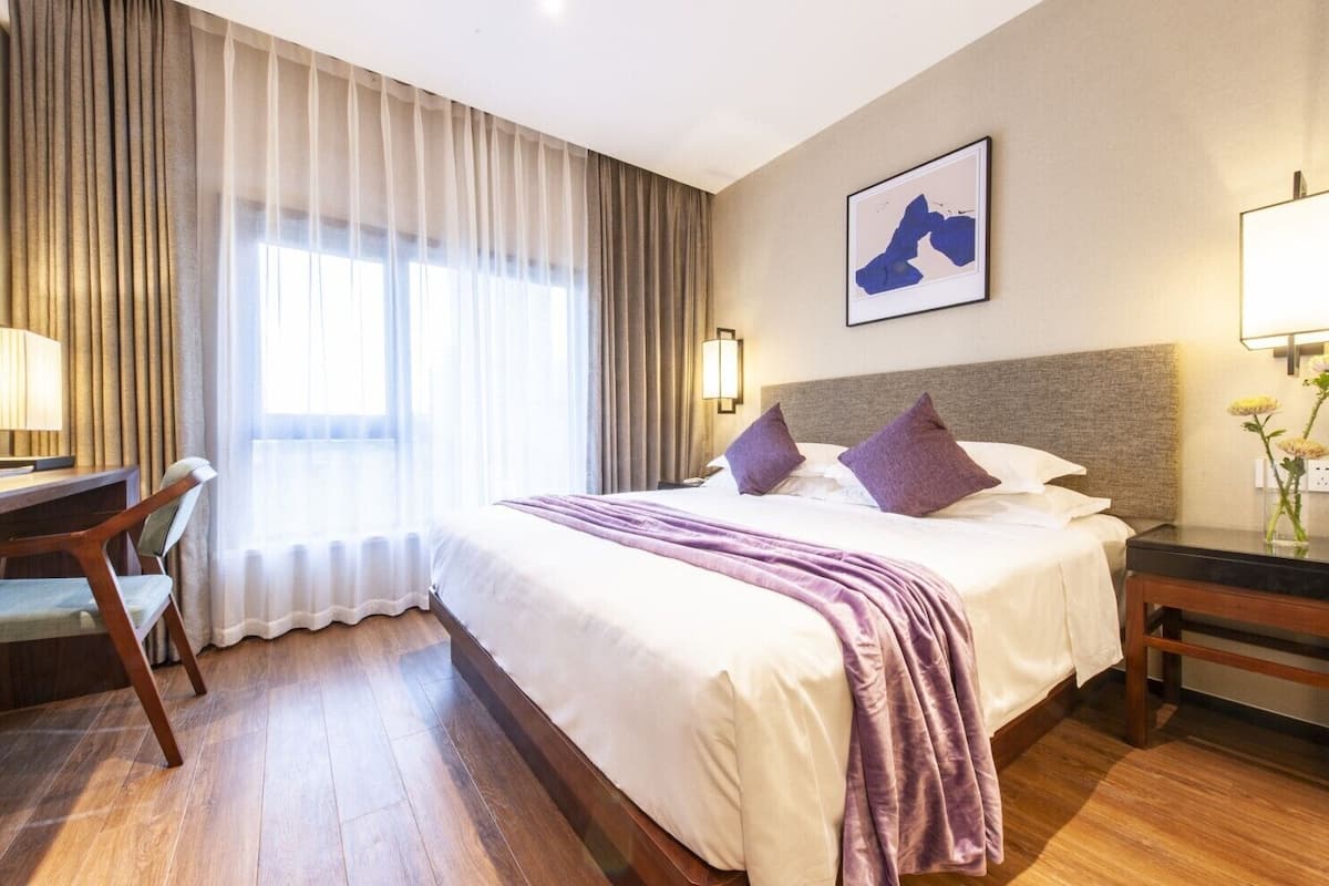 Ein Hotelzimmer mit Bett, Schreibtisch, Stuhl, Lampe und einem Bild an der Wand.