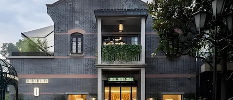 A two-story building with a boutique hotel sign, a balcony with greenery, and a well-maintained garden area.