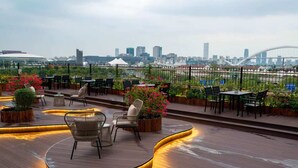 Eine Dachterrasse mit Holzboden, Sitzgelegenheiten im Freien und Kübelpflanzen.