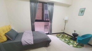 Une chambre à coucher avec un lit, un tapis rond, une chaise bleue, une petite table avec une plante et une fenêtre avec des rideaux.