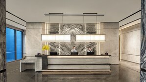 A modern reception desk with marble walls, large windows, and a minimalist design. - Qingshan Lake Tianlan Hotel Hangzhou (Hangzhou)