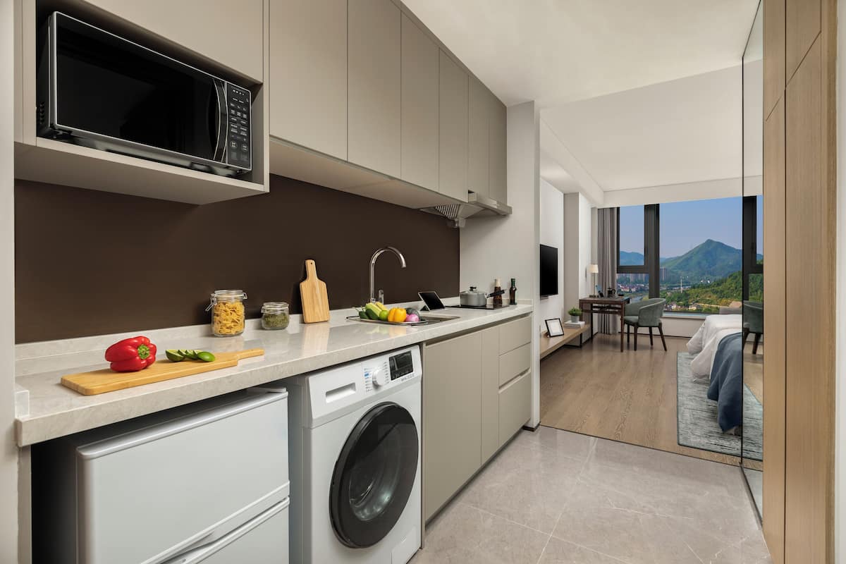 Eine moderne Küche mit Einbauwaschmaschine, Mikrowelle und Spüle. Ein Essbereich bietet Blick auf Berge.