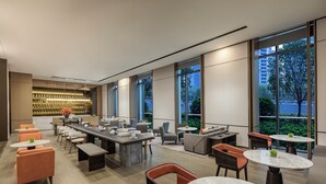 A modern lounge area with multiple seating options, a bar, and large windows offering views of the outdoors. - Qingshan Lake Tianlan Hotel Hangzhou (Hangzhou)