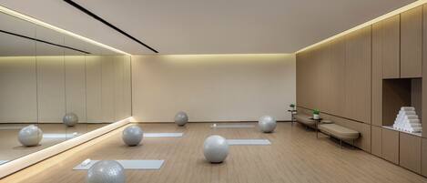 A modern, minimalist room with exercise balls, yoga mats, and a mirror.