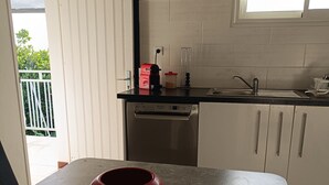 A kitchen with a red bowl on a mat, a coffee maker, and a window with blinds.
