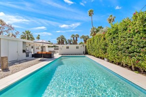 Une piscine avec un bâtiment blanc et un espace extérieur aménagé en arrière-plan.
