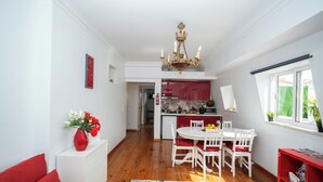 Une cuisine moderne avec des meubles blancs, un coin repas rouge et un lustre.
