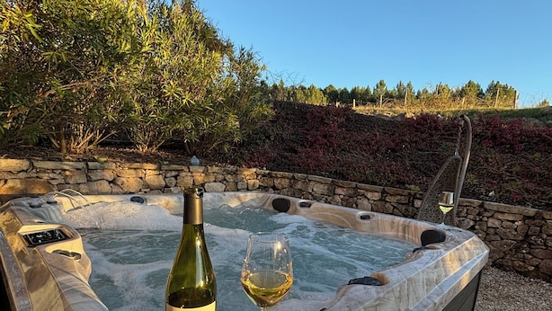 A hot tub with a bottle of Masheritage wine and a glass of wine, surrounded by a stone wall and wooden deck. - Chanvre - Escape and well-being with a private Jacuzzi (Rosières)