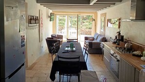 A compact kitchen with a dining area, a refrigerator, a coffee machine, and a view through the glass doors. - Chanvre - Escape and well-being with a private Jacuzzi (Rosières)