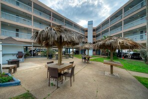 A courtyard with outdoor seating, a pool, and a multi-story building with balconies. - Private Balcony w/ Ocean View | Pool & Hot Tub Access | Ocean Echo by AvantStay (Corpus Christi)