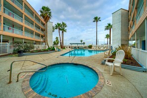 A pool area with multiple levels of balconies, palm trees, and lounge chairs. - Private Balcony w/ Ocean View | Pool & Hot Tub Access | Ocean Echo by AvantStay (Corpus Christi)