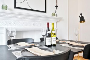Une table à manger est dressée avec des verres à vin, des assiettes et des serviettes, et deux bouteilles de vin sont posées sur la table.