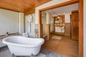 Un baño con bañera independiente, zona de ducha y tocador con espejo.