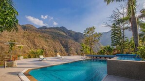 A swimming pool with lounge chairs and a view of mountains. - Raga on the Ganges (Rishikesh)