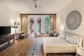 A hotel room with a bed, TV, desk, chair, and a view of the outdoors.